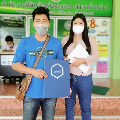 ลูกบ้านถือแฟ้มโอนกรรมสิทธิ์โครงการ deco สีน้ำเงิน ในวันโอนกรรมสิทธิ์
